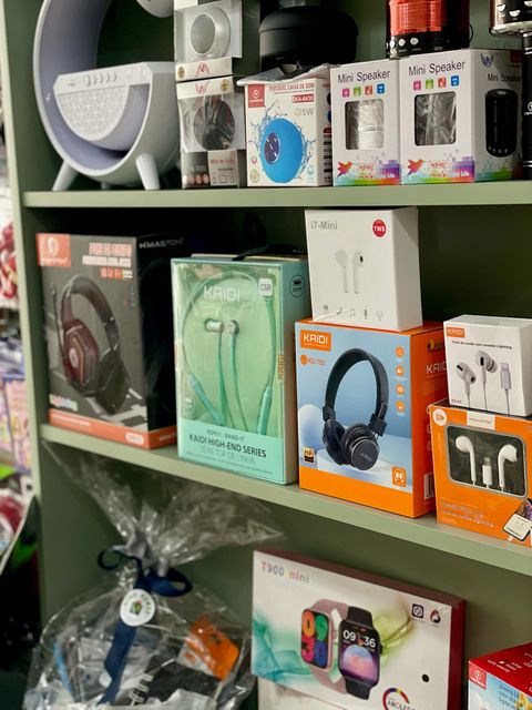 Prateleiras verde-sálvia com headphones Kaidi, caixinhas de som e fones em embalagens laranjas na Mimo Power